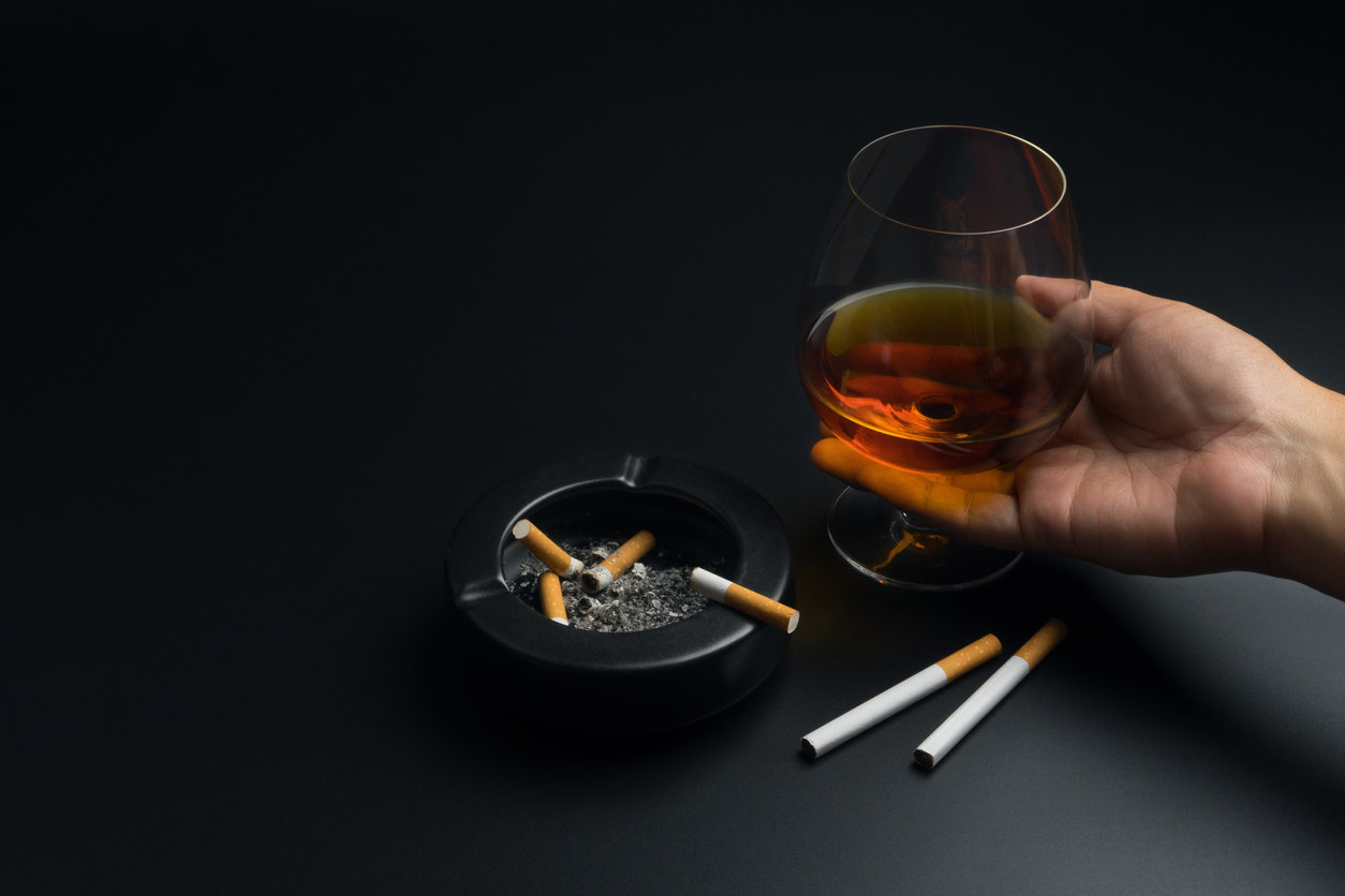 Hand mit Alkohol und Zigaretten